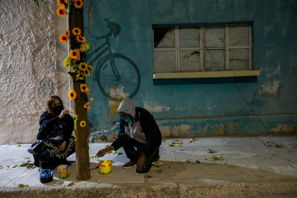 Friends paint a light post where a bike was hung in honor of activist Isabel Cabanillas who was murdered in Juárez in 2020.