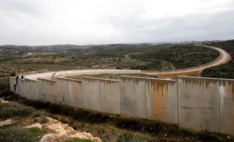 Palestinian demonstrators use a ladder to climb a section of the Israeli barrier during a protest against Trump's Middle East peace plan, in the village of Bilin in the Israeli-occupied West Bank