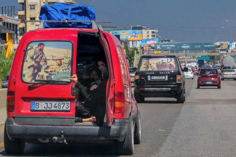 Lebanese Shiite women sit inside a van decorated with a poster of a pro-Iranian Hezbollah fighter, on their way to Beirut after fleeing southern Lebanon. Thousands of families fled southern Lebanon for areas in the capital Beirut and Mount Lebanon, following the expanding Israeli attacks. Marwan Naamani/dpa