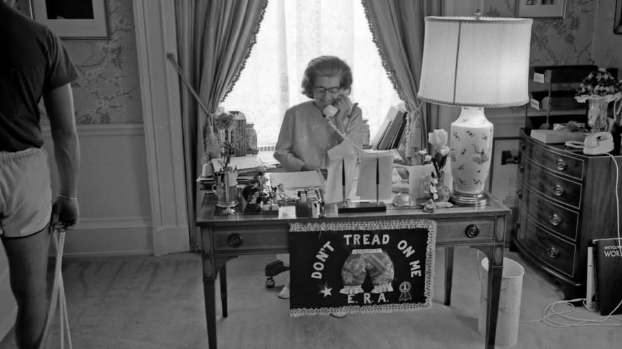 A 1975 photo shows First Lady Betty Ford working at her desk. It is adorned with a flag that reads “Don’t Tread on Me” and “E.R.A.” (Courtesy Gerald R. Ford Presidential Library & Museum)