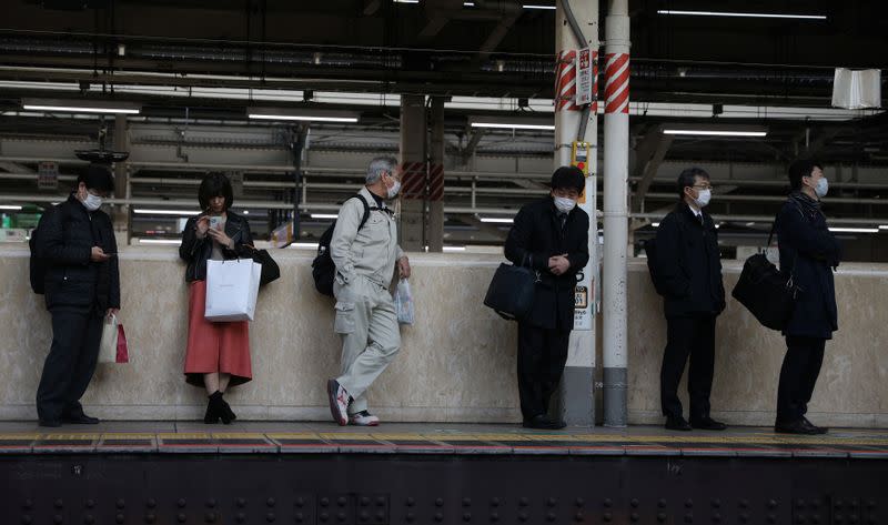 People wearing protective face masks, following an outbreak of the coronavirus, await for their train at the Tokyo station in Tokyo