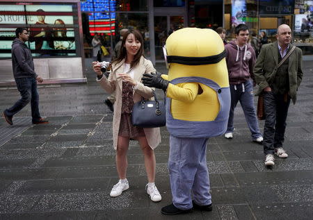 A man dresses as a Minion tries to convince a tourist to have her picture taken with him, in Times Square, in New York, April 7, 2016. REUTERS/Rickey Rogers