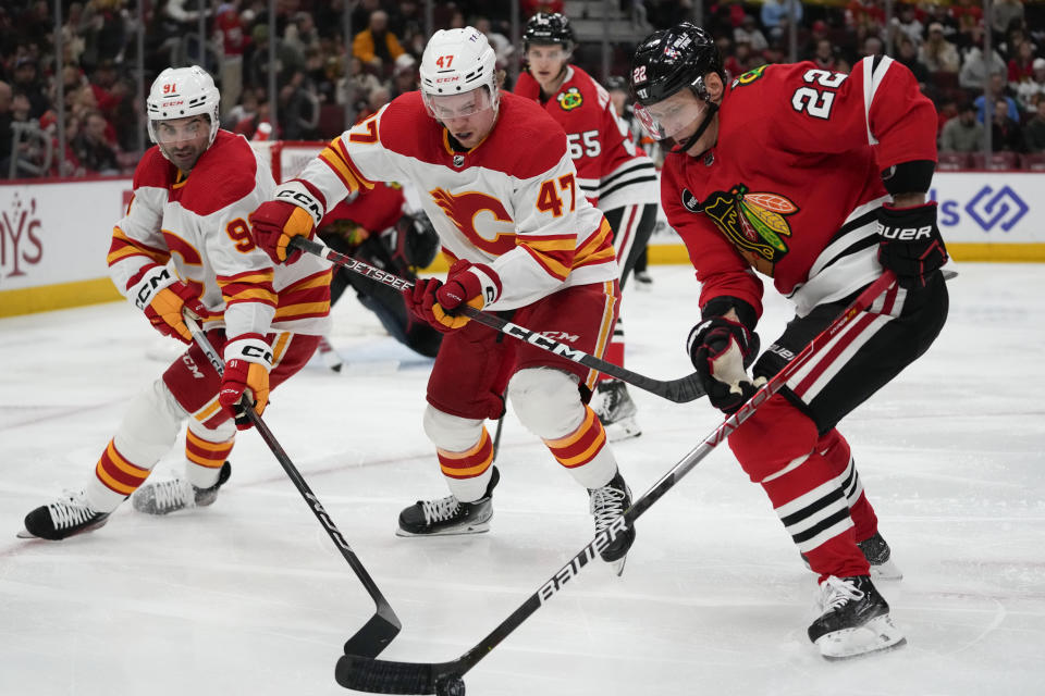 From left to right, Calgary Flames center Nazem Kadri, Calgary Flames center Connor Zary and Chicago Blackhawks defenseman Nikita Zaitsev fight for control of the puck during the second period of an NHL hockey game Sunday, Jan. 7, 2024, in Chicago. (AP Photo/Erin Hooley)