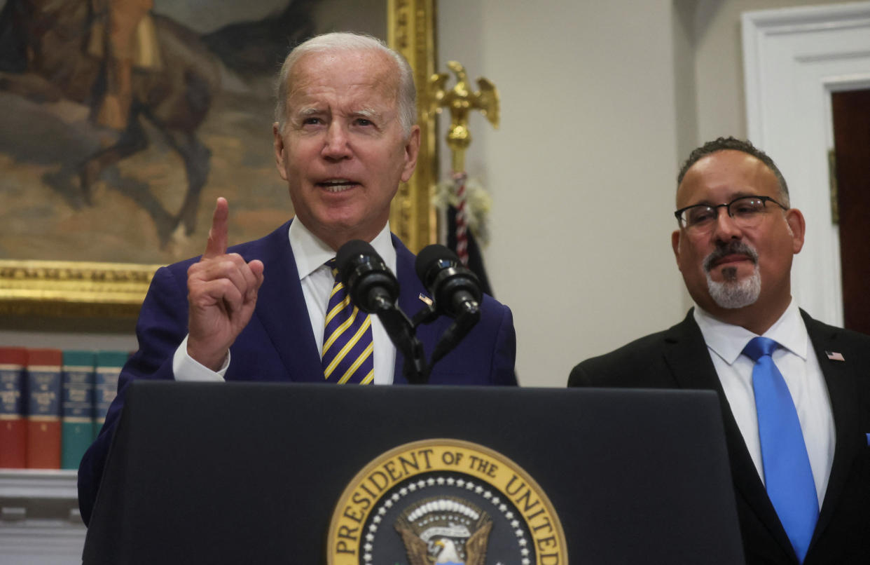 U.S. President Joe Biden is flanked by U.S. Secretary of Education Miguel Cardona as he speaks about administration plans to forgive federal student loan debt during remarks in the Roosevelt Room at the White House in Washington, U.S., August 24, 2022. REUTERS/Leah Millis