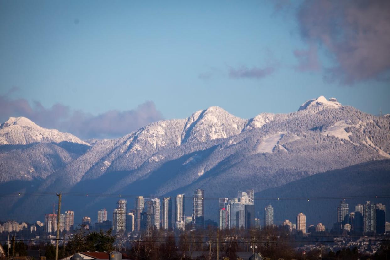 The North Shore mountains are pictured with fresh snow on Thursday, with the Metrotown area of Burnaby, B.C., in the foreground.  (Ben Nelms/CBC - image credit)