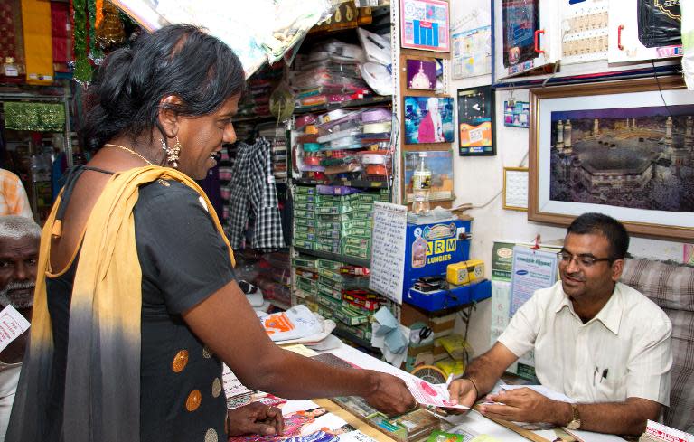 Bharathi Kannamma, 53, a transgender hailing from the Madurai District in southern Tamil Nadu state and who is independently contesting the Lok Sabha elections, distributes pamphlets to a shop owner while campaigning in Madurai, on April 15, 2014