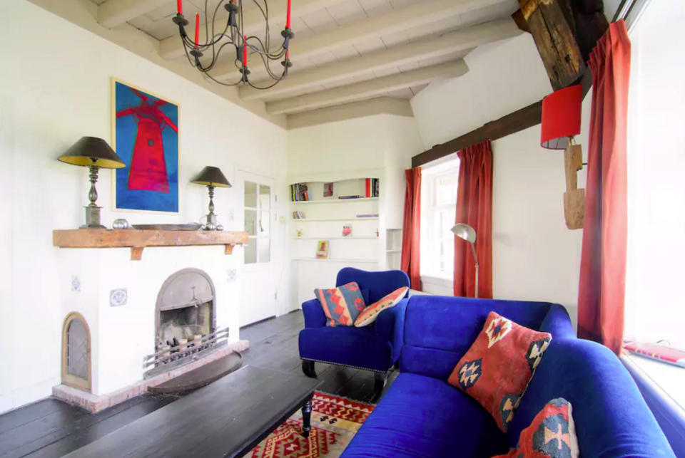 <p>The home’s living room boasts high, beamed ceilings, wood floors and a fireplace. (Airbnb) </p>