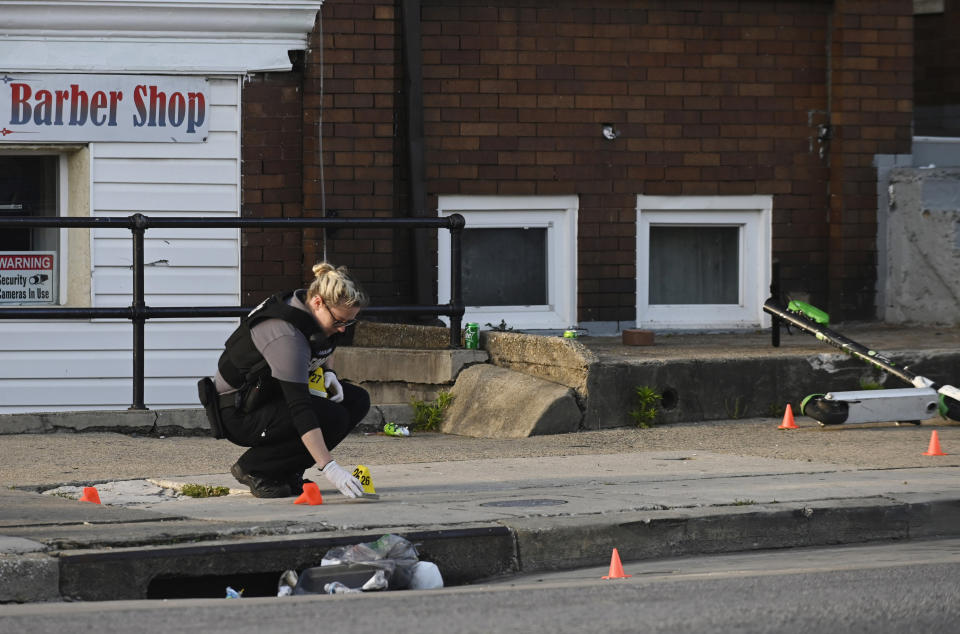 A Baltimore police forensics officer places an evidence marker next to a bullet casing while investigating the scene of a shooting in Baltimore on Sunday, April 28, 2019. A gunman fired indiscriminately into a crowd that had gathered for Sunday afternoon cookouts along a west Baltimore street, killing at least one person and wounding several others, authorities said. (Kenneth K. Lam/The Baltimore Sun via AP)