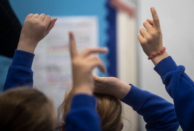 School students with their hands raised during a lesson