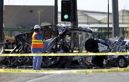 A crew member stands near wreckage at the scene of a double-decker Metrolink train derailment in Oxnard, California February 24, 2015. REUTERS/Jonathan Alcorn