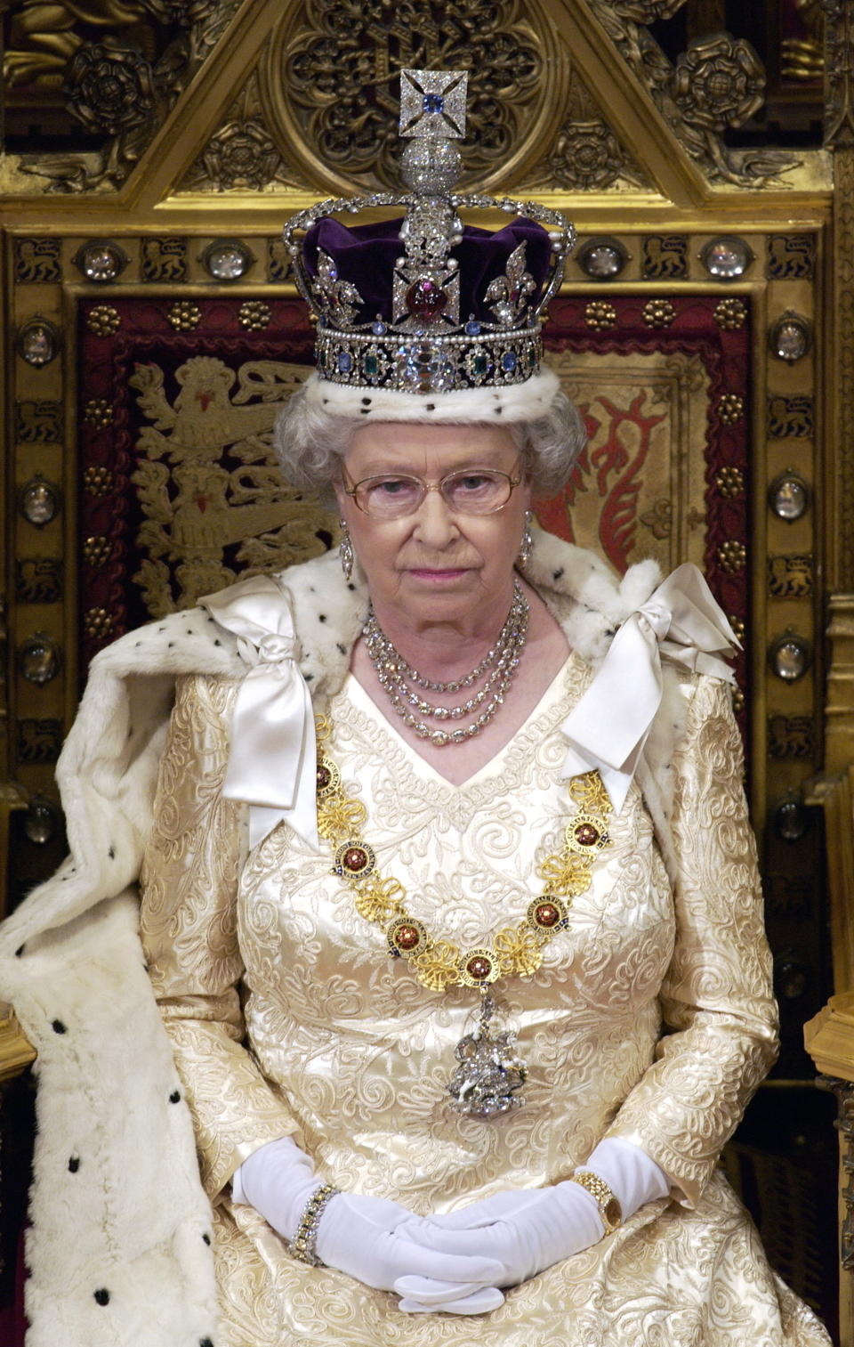 LONDON, UNITED KINGDOM - NOVEMBER 13:  Queen Elizabeth Ll Sitting On A Throne In The House Of Lords, Palace Of Westminster, Waiting To Make Her Speech During The State Opening Of Parliament.  The Queen Is Cream Satin Evening Dress Underneath Ermine-lined Robe Of State With The Imperial State Crown And The Garter Collar With A Diamond George.  (Photo by Tim Graham Photo Library via Getty Images)