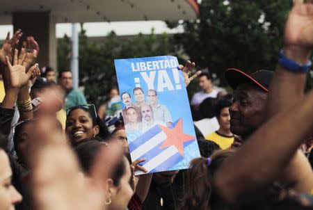 People cheer for the "Cuban Five" while holding a poster of the five Cuban intelligent agents, in Havana December 17, 2014. REUTERS/Stringer