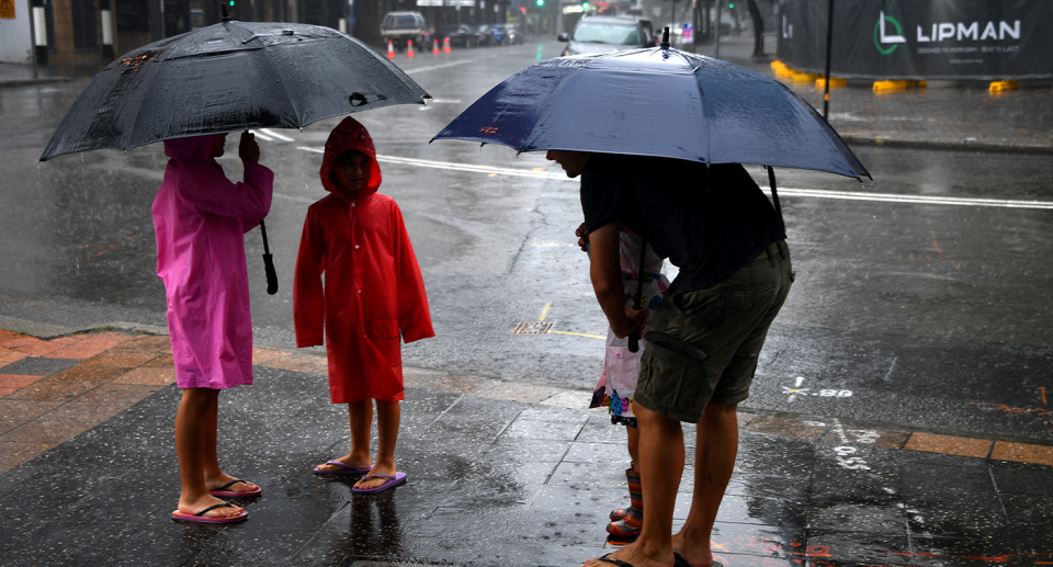 A family standing under umbrellas in an Australian city.