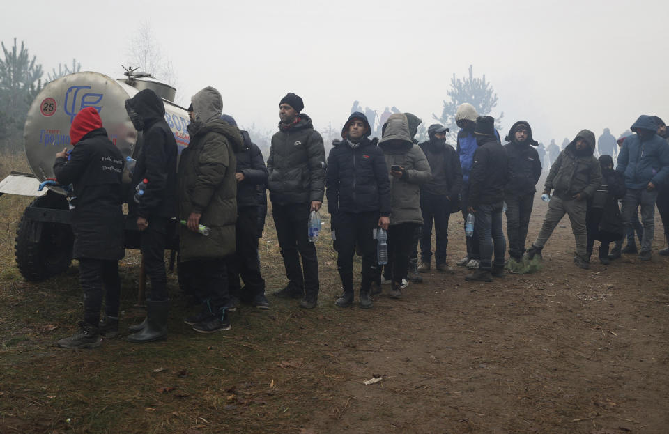 Migrants from the Middle East and elsewhere stand in line to a drinking water tank at the Belarus-Poland border near Grodno, Belarus, Thursday, Nov. 11, 2021. The European Union has accused Belarus' authoritarian President Alexander Lukashenko of encouraging illegal border crossings as a "hybrid attack" to retaliate against EU sanctions on his government for its crackdown on internal dissent after Lukashenko's disputed 2020 reelection. (Ramil Nasibulin/BelTA pool photo via AP)