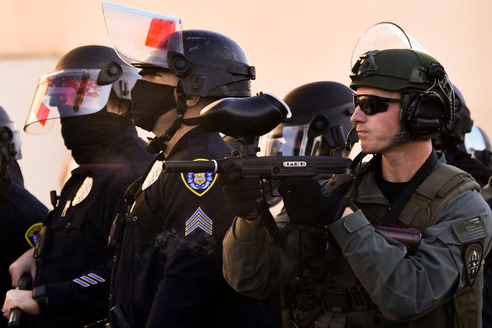 A pepper ball (L), exits the barrel of a San Diego Police Department (SDPD) officer's Tippmann FT-12 paintball gun while firing pepper balls towards counter-protesters at a "Patriot March" demonstration, Jan. 9, 2021 in the Pacific Beach neighborhood of San Diego, California.