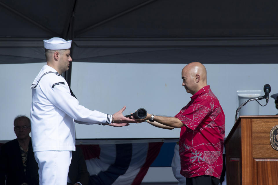 Ken Inouye, son of Daniel Inouye, right, passes the Long Glass to Petty Officer Vitaly Ivanovsky during the commissioning ceremony for the USS Daniel Inouye, named after the long-serving U.S. senator from Hawaii and decorated World War II veteran, at Pearl Harbor, Hawaii on Wednesday, Dec. 8, 2021. (Craig T. Kojima/Honolulu Star-Advertiser via AP)