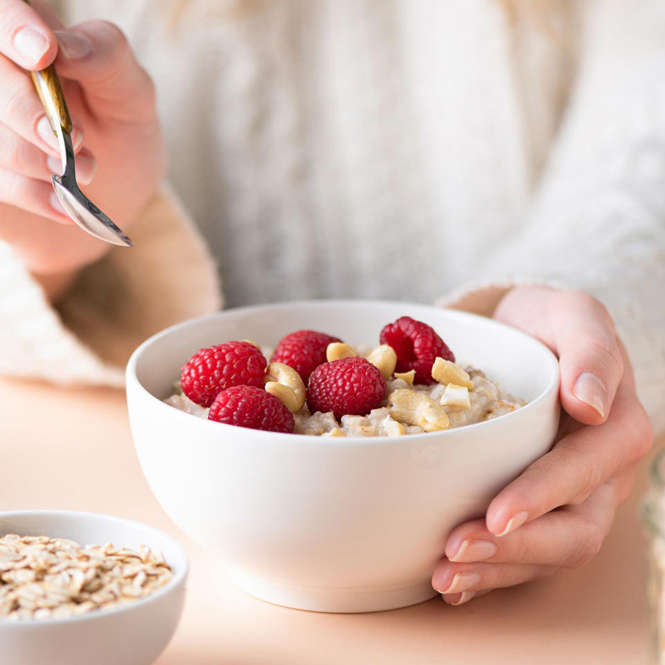 woman eating bowl of oatmeal topped with berries