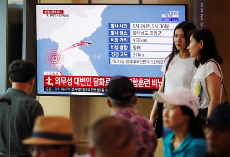 People watch a TV broadcasting a news report on North Korea firing two unidentified projectiles, in Seoul