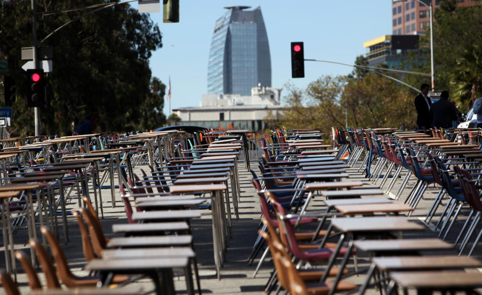 School desks placed by parents, district graduates and activists block a street in front of the Los Angeles Unified School District headquarters in a demonstration against student dropout rates Tuesday, April 8, 2014, in downtown Los Angeles. Protest organizers say the 375 desks are there to represent the 375 students who drop out of the district every week during the school year. (AP Photo/Richard Vogel)