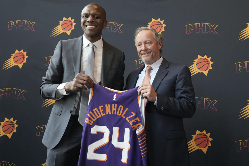 New Phoenix Suns head coach Mike Budenholzer, right, and James Jones, left, Suns president of basketball operations and general manager, hold up a new Budenholzer uniform during an NBA news conference introducing Budenholzer, Friday, May 17, 2024, in Phoenix. (AP Photo/Ross D. Franklin)