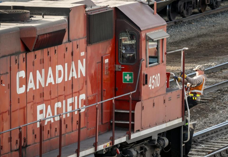 An employee boards a Canadian Pacific Railway locomotive at a yard in Calgary, Alta., Friday, March 18, 2022.