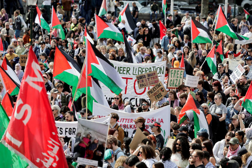 Demonstrators hold signs and Palestinian flags