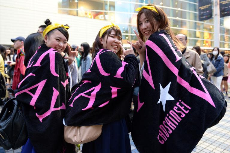 Three Japanese fans of K-Pop group Supernova wait outside the Yokohama Arena for the K-Pop chart show "M Countdown" on April 2, 2014