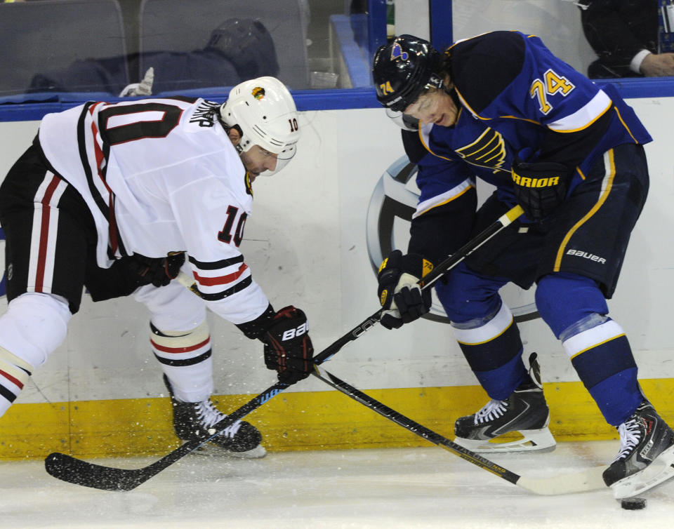 St. Louis Blues' T.J. Oshie (74) and Chicago Blackhawks' Patrick Sharp (10) reach for the puck during the second period in Game 2 of a first-round NHL hockey playoff series on Saturday, April 19, 2014, in St. Louis. (AP Photo/Bill Boyce)