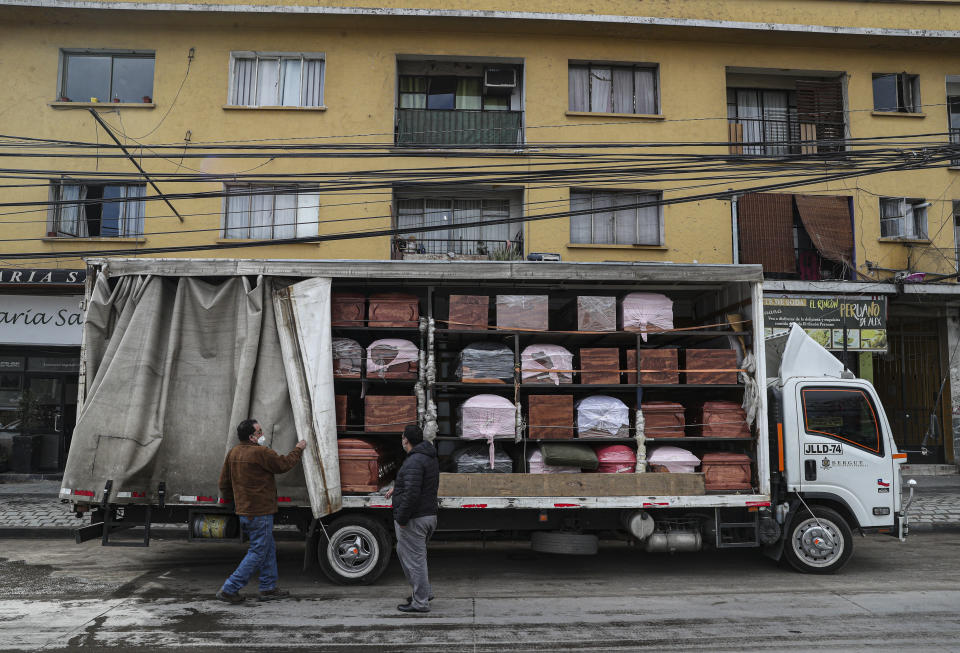Bergut Funeral Services employees deliver coffins to a funeral store in Santiago, Chile, Friday, June 19, 2020. Coffin production has increased 120%, according to owner Nicolas Bergerie. A basic coffin penned the COVID model was designed to cope with the increase of deaths during the new coronavirus pandemic. (AP Photo/Esteban Felix)