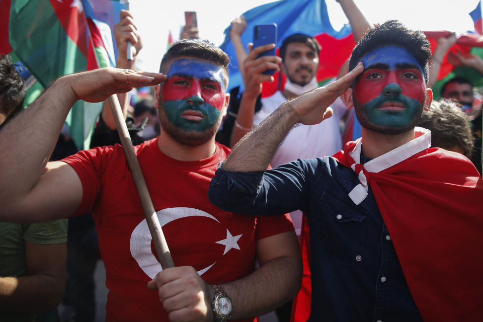 Demonstrators, their faces covered with the colours of the flag of Azerbaijan, salute during a protest supporting Azerbaijan, in Istanbul, Sunday, Oct. 4, 2020. Armenian and Azerbaijani forces continue their fighting over the separatist region of Nagorno-Karabakh, following the reigniting of a decades-old conflict. Turkey, which strongly backs Azerbaijan, has condemned an attack on Azerbaijan's second largest city Gence and said the attack was proof of Armenia's disregard for law. (AP Photo/Emrah Gurel)