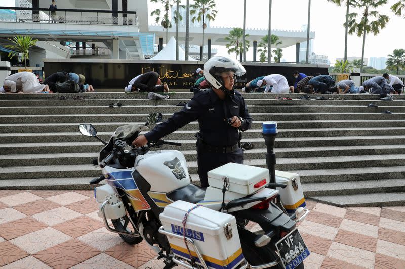 A police officer arrives to disperse Muslims praying outside the closed National Mosque while celebrating Eid al-Fitr, the Muslim festival marking the end the holy fasting month of Ramadan, amid the coronavirus disease (COVID-19) outbreak in Kuala Lumpur