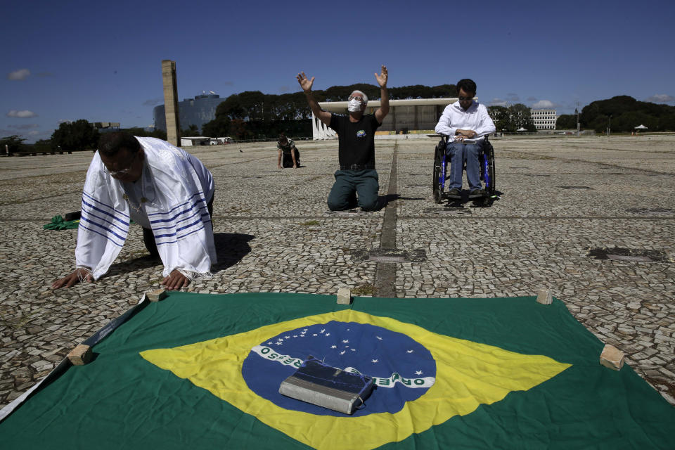 Evangelicals from the Fountain of Faith church pray for Brazil's President Jair Bolsonaro outside Planalto presidential palace in Brasilia, Brazil, Tuesday, April 28, 2020. Brazil’s Supreme Court on Monday night authorized an investigation into whether Bolsonaro committed crimes by allegedly attempting to interfere with the country’s Federal Police. (AP Photo/Eraldo Peres)