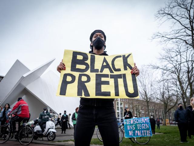 Black protestors holds up a sign in Dutch during a demonstration.
