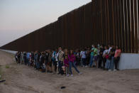 A group of migrants stand next to the border wall as they wait to get taken away by the Border Patrol in Eagle Pass, Texas, Saturday, May 21, 2022. The Eagle Pass area has become increasingly a popular crossing corridor for migrants, especially those from outside Mexico and Central America, under Title 42 authority, which expels migrants without a chance to seek asylum on grounds of preventing the spread of COVID-19. (AP Photo/Dario Lopez-Mills)