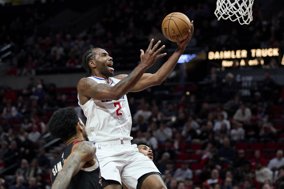 Los Angeles Clippers forward Kawhi Leonard shoots from between Portland Trail Blazers guard Anfernee Simons, left, and forward Toumani Camara during the second half of an NBA basketball game in Portland, Ore., Wednesday, March 20, 2024. (AP Photo/Craig Mitchelldyer)