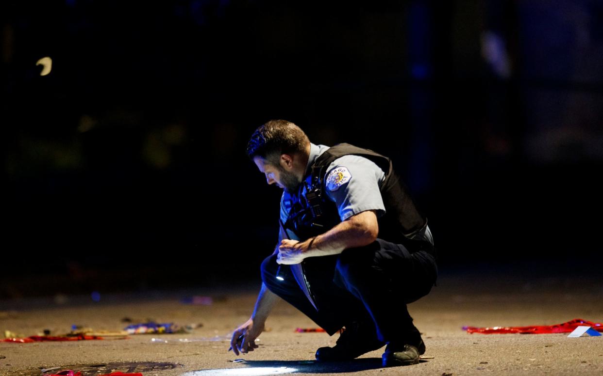 An officer investigates the scene of a shooting in Chicago on Sunday - AP