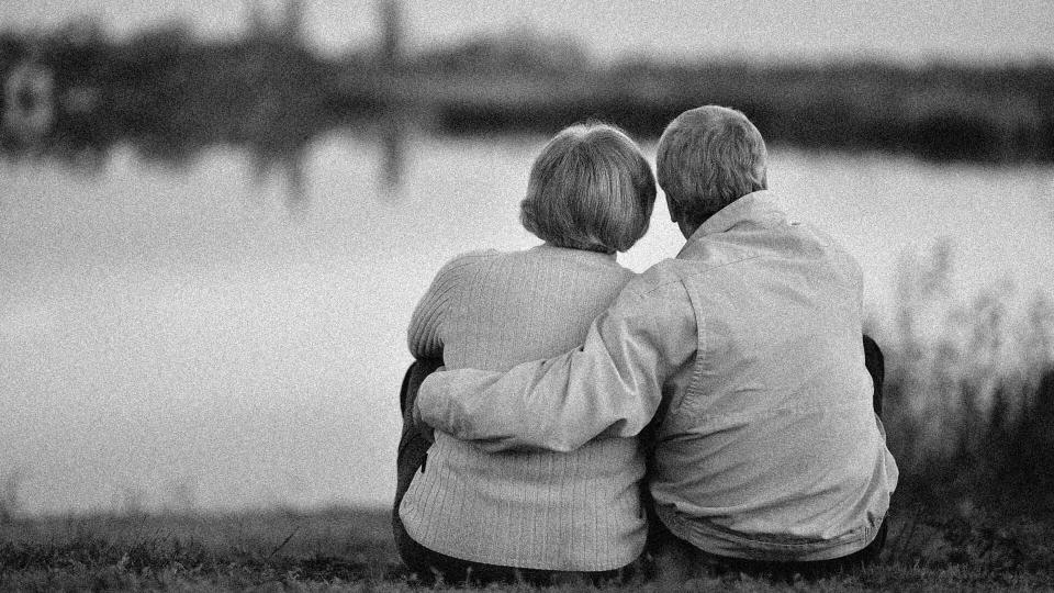 happy couple sitting together beside a lake