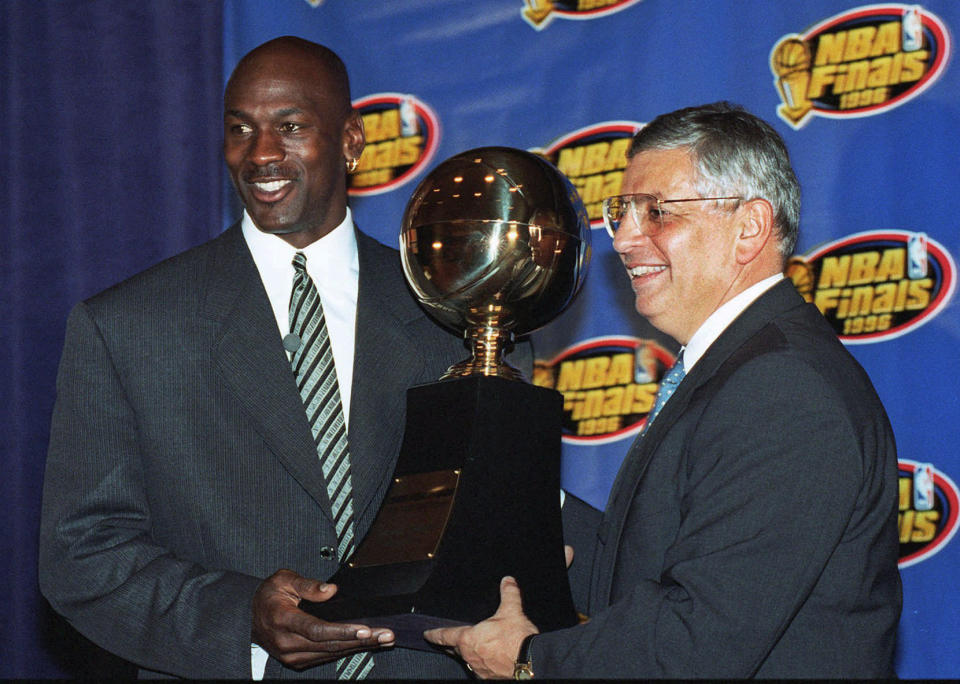 FILE - In this June 18, 1996, file photo, Chicago Bulls' Michael Jordan, left, receives the NBA Finals Most Valuable Player trophy from Commissioner David Stern during a ceremony in Chicago. David Stern, who spent 30 years as the NBA's longest-serving commissioner and oversaw its growth into a global power, has died on New Year’s Day, Wednesday, Jan. 1, 2020. He was 77. (AP Photo/Charles Bennett, File)