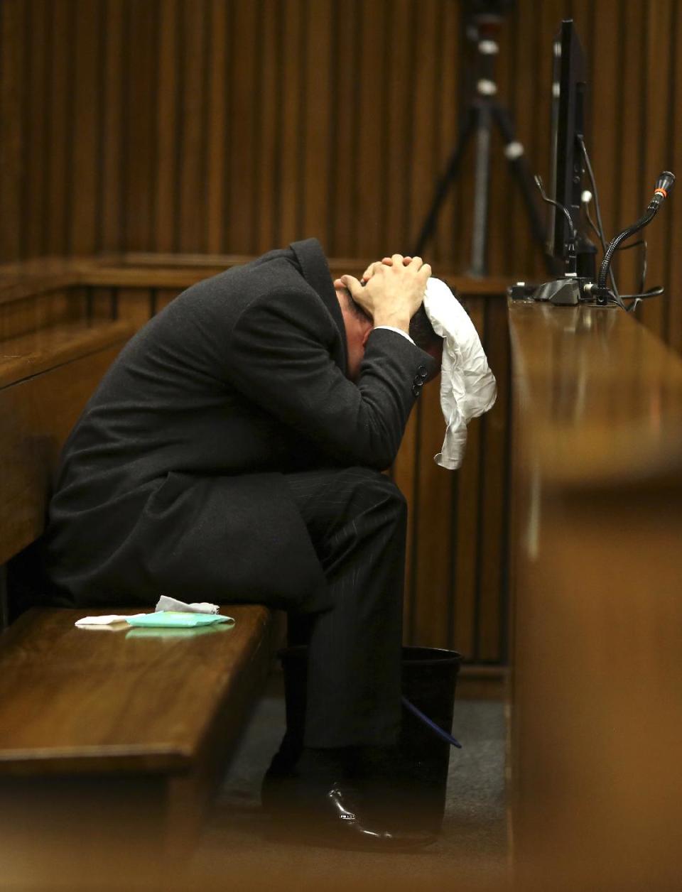 Oscar Pistorius covers his head with a handkerchief after he had reached for a bucket at his feet while listening to cross questioning about the events surrounding the shooting death of his girlfriend Reeva Steenkamp, in his second week in court during his trial in Pretoria, South Africa, Monday, March 10, 2014. Pistorius is charged with the shooting death of his girlfriend Steenkamp, on Valentines Day in 2013. (AP Photo/Siphiwe Sibeko, Pool)