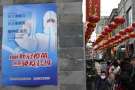 A child wearing a mask to protect from COVID-19 passes by a poster with the slogan "Receive COVID-19 vaccination, jointly built an Immunity Great Wall" in Beijing on Feb. 14, 2021. If China is to meet its tentative goal of vaccinating 80% of its population against the coronavirus by the end of the year, tens of millions of children may have to start rolling up their sleeves. (AP Photo/Ng Han Guan)