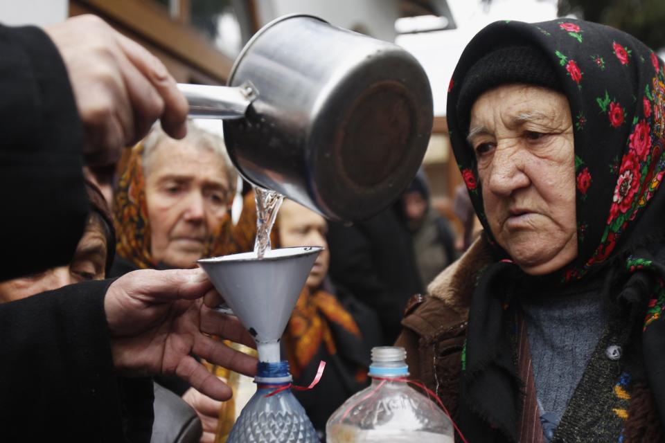 Orthodox believers take holy water at a church on Epiphany Day in Pietrosani