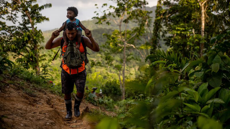 A guide carries the child of Haitian migrants through the Darién Gap, February 2023.