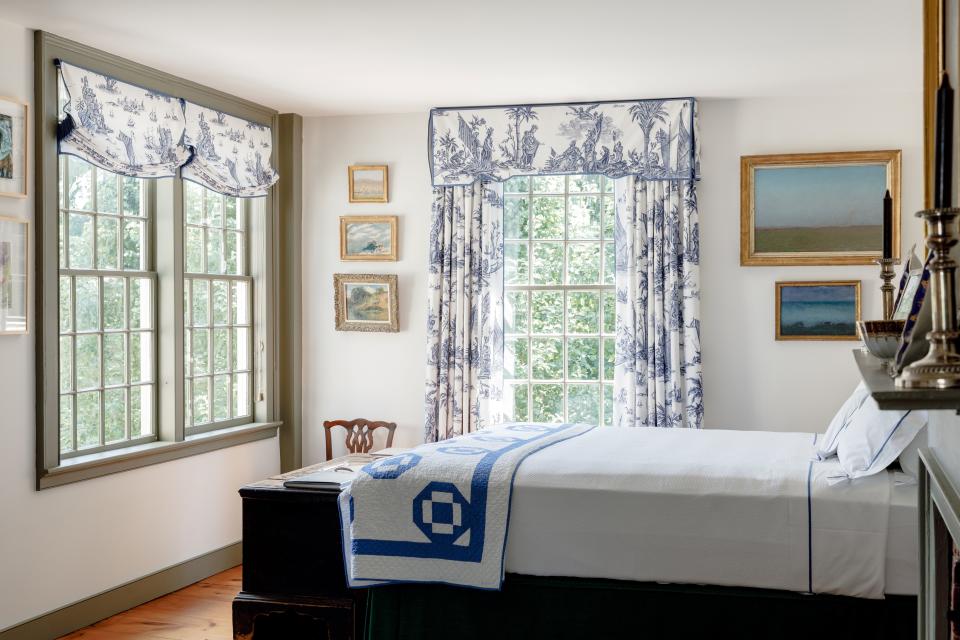 The master bedroom pairs the Burger fabric with a 1930s-era quilt in a matching blue and white pattern. The paintings are mix of 19th-century English landscapes and 18th-century American portraits.