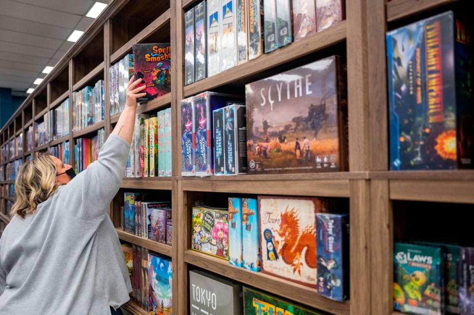 Jan Martinell, who owns Cole Street Game Vault with her husband Chad, stocks the shelves on Friday night in downtown Enumclaw. The store features hundreds of board games and card games for all ages and abilities.