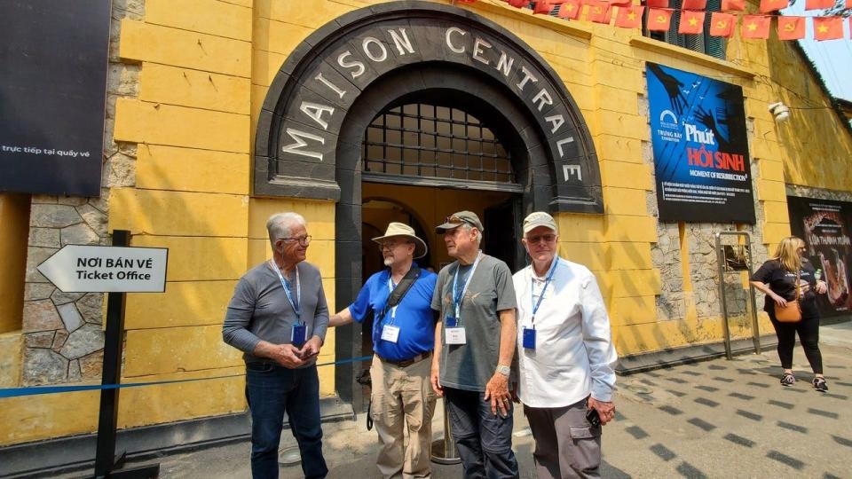 Four former Vietnam War POWs in front of the gates of the one-time 'Hanoi Hilton' prison in 2023. Left to right: Albert Molinare, David Drummond, William Shanker, and Robert Certain.