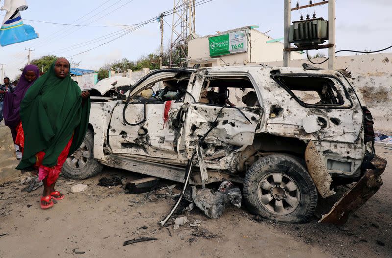 FILE PHOTO: Somali women walk near the wreckage of a car destroyed at the scene of a militant attack at the Elite Hotel in Lido beach, in Mogadishu