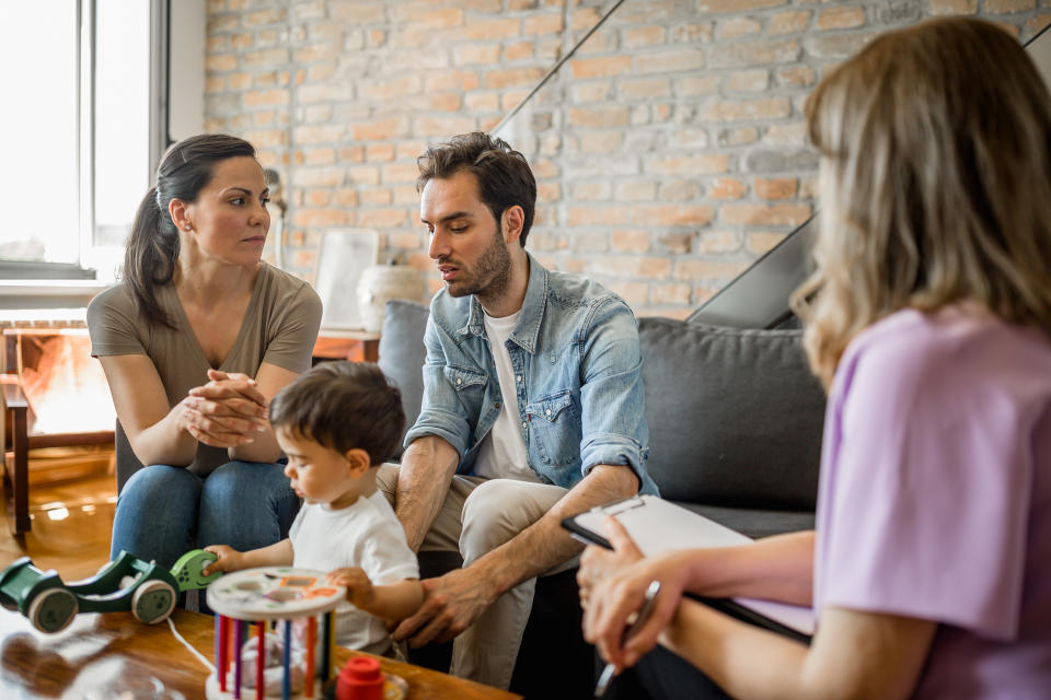 A young couple sits with their toddler and talks with a social worker