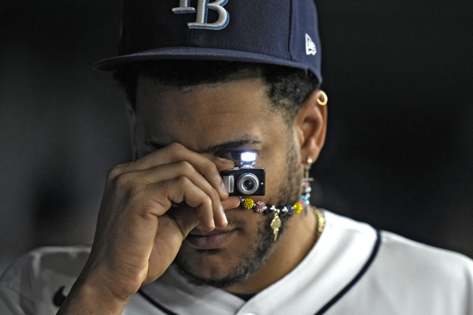 Tampa Bay Rays' Jose Siri takes a picture of teammates with a tiny camera during the fourth inning of a baseball game against the Minnesota Twins Thursday, June 8, 2023, in St. Petersburg, Fla. (AP Photo/Chris O'Meara)