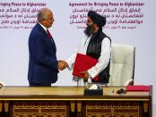 Mullah Abdul Ghani Baradar, the leader of the Taliban delegation, and Zalmay Khalilzad, U.S. envoy for peace in Afghanistan, shake hands after signing an agreement at a ceremony between members of Afghanistan's Taliban and the U.S. in Doha