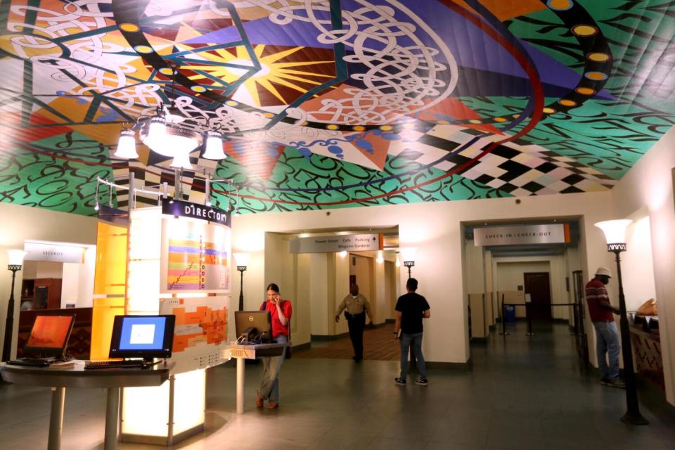 Visitors are seen underneath an art piece on the ceiling inside a room